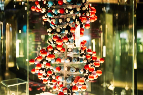 Vista de perto do modelo de DNA, estrutura com muitos balões coloridos em fundo verde. — Fotografia de Stock