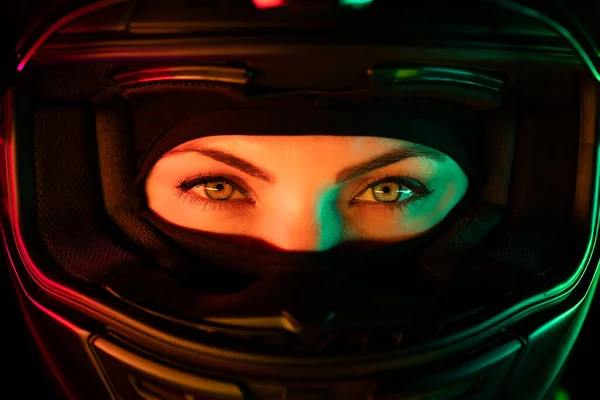 Retrato de mulher motociclista confiante em capacete de motocicleta fechado. Jovem motociclista motorista olhando para a câmera sob luz colorida neon à noite. — Fotografia de Stock