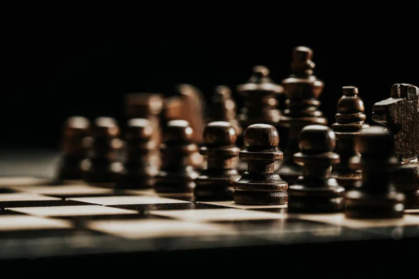 Pieces on chessboard. Board intelligence game - wooden chess on dark background. Business solutions, challenge, sport, success strategy concept. — Stockfoto