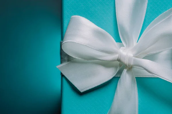 Elegante caja azul regalo de lujo atada con cinta de seda sobre fondo turquesa. Regalo de cumpleaños, aniversario, tarjetas, postales, concepto de papel pintado. — Foto de Stock