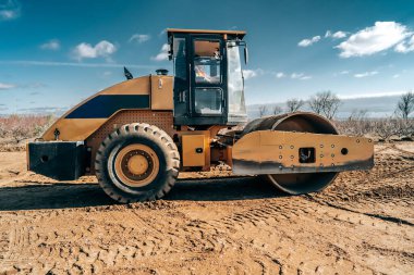 Titreşimli tekerlekli yeni toprak yol inşaatı manzarası. Yol yüzeyi tamiri. Ağır makineler kavramı.