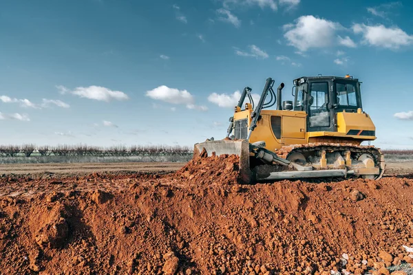Crawler bulldozer working on construction site or quarry. Mining machinery moving clay, smoothing gravel surface for new road. Earthmoving, excavations, digging on soils. — Stock Photo, Image