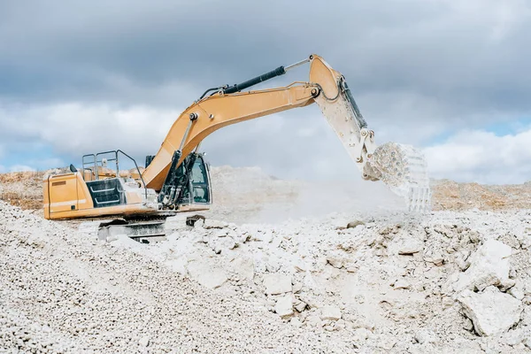 Graafmachine met grote emmer giet steen in draagbare verpletterende zeefinstallatie op bouwplaats of steengroeve. Mijnbouw zware machines details. Grondverzet, opgravingen, graven op bodems. — Stockfoto