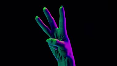 Kadın eli, siyah arka planda 3 parmağı olduğunu gösteriyor. Bir, iki, üç rakam jesti, reade set, matematik konsepti.. 