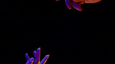 Toprak yaratma fikri. Eller uzanıyor, siyah ve neon renkli ışıkta parmaklarını birleştiriyor. Erkek ve kadın, aşk, din. Çağdaş sanat, evrim, köken kavramı.