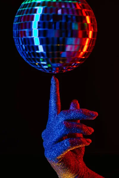 Vrouw met draaiende disco spiegelbal op vinger onder de neon. Glanzende zilveren bol reflecteert licht. Retro avond feest, muziek en entertainment concept achtergrond — Stockfoto