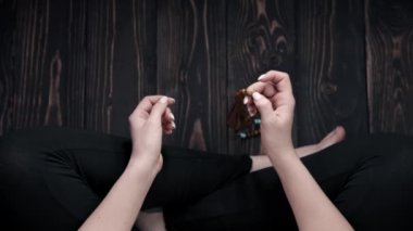 Kadın nilüfer pozisyonunda oturur ve meditasyon yapar, mantraları okurken ahşap mala boncukları kullanır. Üst Manzara. Maneviyat, din, Tanrı kavramı..