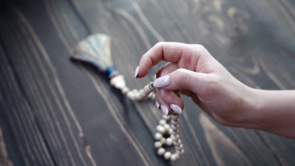 La mano iluminada por la mujer cuenta malas hebras de perlas de madera usadas para mantener la cuenta durante las meditaciones del mantra. La señora se sienta en el suelo de madera. Espiritualidad, religión, concepto de Dios. — Vídeos de Stock
