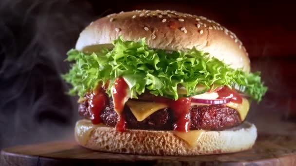 Leckerer Burger mit Rauch, Fast-Food-Konzept. Frisch gegrillter Hamburger vom Grill mit Fleischpatty, Tomaten, Gurken, Salat, Zwiebeln und Sesam. Ungesunder Lebensstil. Lebensmittel-Hintergrund. Dolly erschossen — Stockvideo