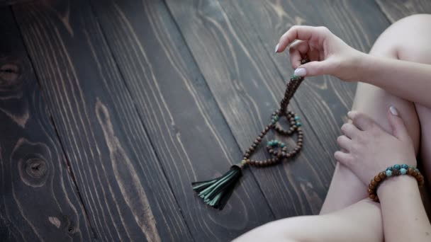 Frau zündet Hand zählt Mala-Perlen Stränge von Edelsteinen, die für die Zählung während Mantra-Meditationen verwendet werden. Lady sitzt auf Holzboden. Spiritualität, Religion, Gotteskonzept. — Stockvideo