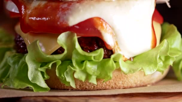 La sauce déborde de gros hamburger appétissant avec escalope de viande, oignon, légumes, fromage fondu, laitue et mayonnaise. Hamburger, vue rapprochée. Concept de restauration rapide. — Video