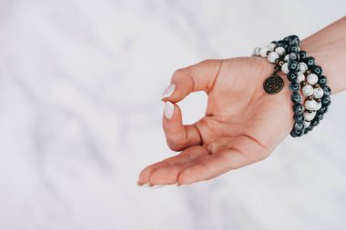 Jnana Gian Mudra - Beyaz arka planda Om. Mala boncuklu bileziği olan bir kadın. Kadın meditasyon yapıyor, yoga yapıyor.