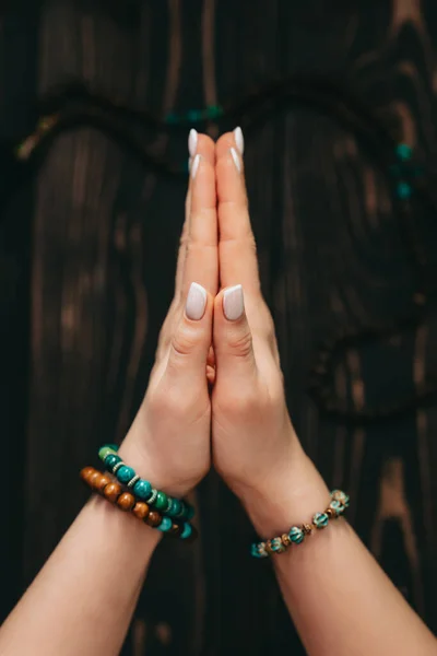 Frau liest Mantren oder Gebete, die Hände in Namaste vor Rosenkranz oder Mala-Perlen auf Holzgrund gefaltet. Spiritualität, Religion, Gotteskonzept. — Stockfoto