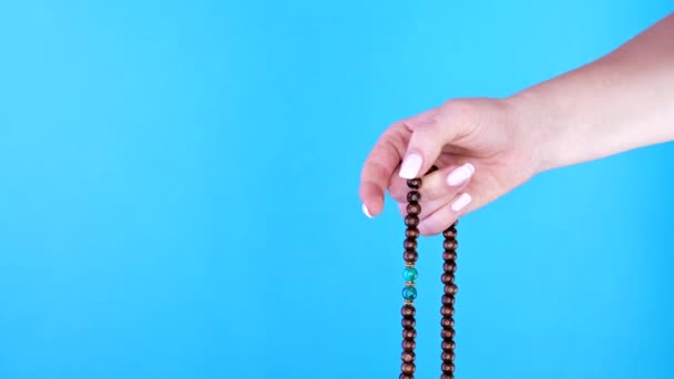 Die Hand der Frau zählt Mala-Perlen-Stränge, die während Mantra-Meditationen zur Zählung verwendet werden. Blauer Hintergrund. Spiritualität, Religion, Gotteskonzept. — Stockvideo
