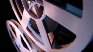 Film dönüşümlü makaraları yakın çekim. Analog oynatıcı. Karanlık ev sinemasında oynayan eski moda 8 mm film projektörü. Eski nesneler, sinema, sinematograf konsepti