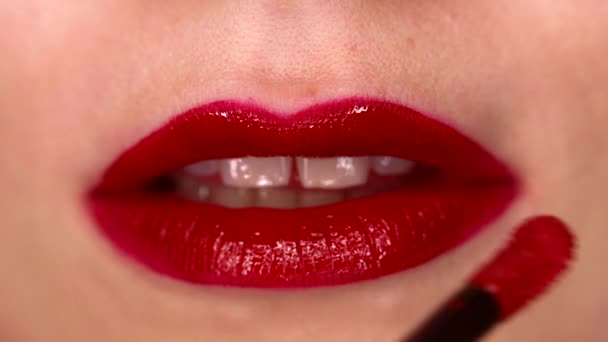 Femme appliquant du gloss rouge liquide ou du rouge à lèvres sur les lèvres sexy naturelles. Sourire lumineux. Fermez la bouche féminine sensuelle. Maquillage publicitaire, beauté, concept cosmétique — Video