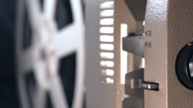  Eski moda 8 mm film projektörü. Kaset filmi gösteriyor. Işık huzmesi yansıtılıyor. Ev sineması, yayın, dönen bobinler. Eğlence, nostalji, festival ekipmanları konsepti