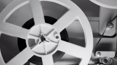 Dönen film bobbin monokrom görüntüleri. Analog oynatıcı. Eski moda 8 mm 'lik projektör ev sinemasında film oynuyor. Eski nesneler, sinema, eğlence, nostalji konsepti