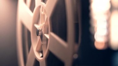 Film makarası dönüyor. Analog oynatıcı. Eski moda 8 mm 'lik projektör ev sinemasında film oynuyor. Eski nesneler, sinema, eğlence, nostalji konsepti