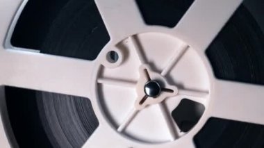 Bantla çevrilmiş bobinlerin görüntüsü. Analog oynatıcı. Tiyatroda eski moda 8 mm 'lik projektör oynuyor. Eğlence, nostalji, festival, yayın ekipmanları. Dolly vurdu.