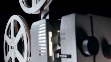 Tiyatroda 8mm 'lik film projektörü karanlıkta oynuyor. Dönüşümlü beyaz makaralar. Analog oynatıcı. Eski usul. Eski nesneler, eğlence, nostalji, festival ekipmanları konsepti