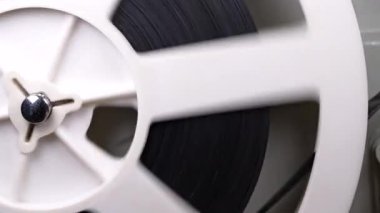 Retro eski moda 8 mm 'lik projektör kaset filmiyle makara oynuyor. Sarmalı yakın çekimde çeviriyorum. Eski nesneler, eğlence, nostalji, festival ekipmanları