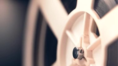 Dönüşümlü beyaz makaralar. Analog oynatıcı. Eski moda 8mm film projektörü. Ev sinemasında karanlıkta bobbin bandı çalıyor. Eski nesneler, sinema, sinematograf konsepti