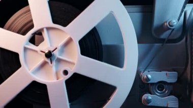 Dönüşümlü beyaz makaralar. Analog oynatıcı. Eski moda 8mm film projektörü ev sinemasında karanlıkta oynuyor. Eski nesneler, sinema, sinematograf konsepti