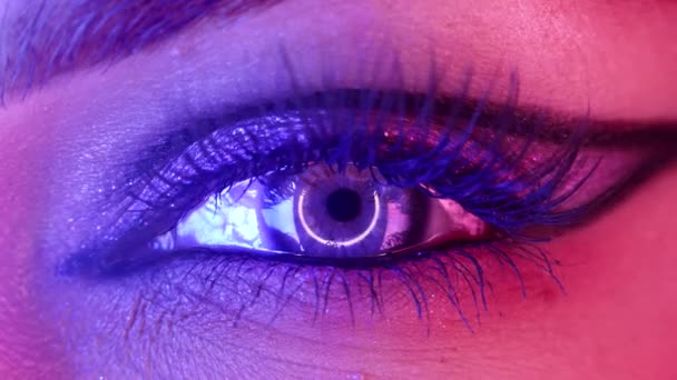 Macro of woman eye with glitter shiny make-up. Long false lashes, neon light. Lady, colorful cornea with round reflection. Fashion model, female beauty and uniqueness — Stock Video