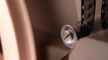 Çalışma sürecinin yakın plan detaylı görüntüsü eski moda 8mm projektör kaset filmiyle makara oynuyor. Bobin dönüyor. Eski nesneler, eğlence, nostalji, festival ekipmanları