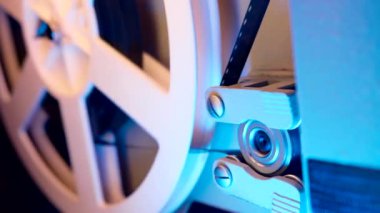 Çalışma sürecinin yakın plan detaylı görüntüsü eski moda 8mm projektör kaset filmiyle makara oynuyor. Bobin dönüyor. Eski nesneler, eğlence, nostalji, festival ekipmanları