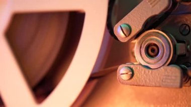 Çalışma sürecinin yakın plan detaylı görüntüsü eski moda 8mm projektör kaset filmiyle makara oynuyor. Bobin dönüyor. Eski nesneler, eğlence, nostalji, festival ekipmanları