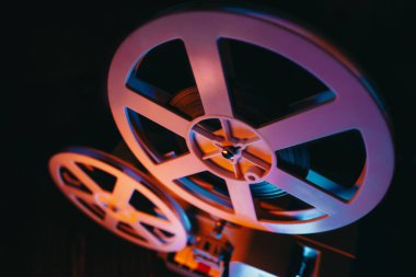 Film makaraları dönüyor. Analog çalar, bantlı teneke kutular. Eski moda 8 mm 'lik projektör ev sinemasında film oynuyor. Klasik nesneler, festival ekran koruyucusu ve yayın ekipmanları için mükemmel.