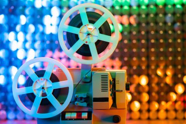 Renkli, parıldayan duvarda dönen bir film makarası. Eski moda 8 mm film projektörü sim odasında oynuyor. Eski nesneler, Oscar, sinema, Hollywood konsepti