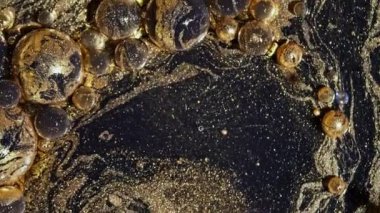 Altın boya ve parıltılı baloncuklardan oluşan koyu mermer bir girdap. Yağ küreleri hareket ediyor, çözülüyor, patlıyor. Gezegenlerin şekilleri. Ayrıntılı doku arkaplanı, güzel galaksi tasarımı. 