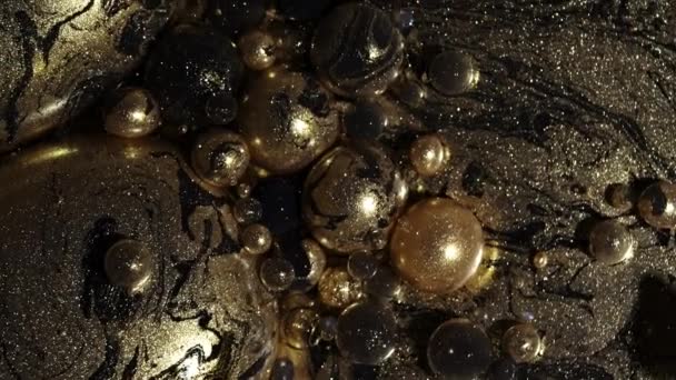 Μαύρο μαρμάρινο αφηρημένο στροβιλισμό χρυσών χρωμάτων και φυσαλίδων γκλίτερ. Οι σφαίρες πετρελαίου κινούνται, διαλύονται, εκρήγνυνται. Σχήματα πλανητών. Λεπτομερής υφή φόντου, όμορφο σχεδιασμό γαλαξία. — Αρχείο Βίντεο