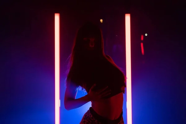 Сексуальна жінка танцює на світлому фоні світлодіодних ламп. Вона виглядає спокусливо. Блакитна димова студія . — стокове фото
