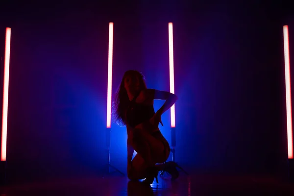 Sexy vrouw dansen op gloeiende led-lampen achtergrond. Ze lijkt verleidelijk. Blauwe rokerige studio. — Stockfoto