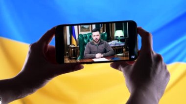 Nisan 2022 - Kherson, Ukrayna. Başkan Volodymyr Zelensky 'nin Ukrayna bayrağı geçmişinde yaptığı akıllı telefon konuşmasını izliyorum. Haberler. Rus saldırganlığı. Savaş tehdidi..