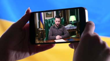 Nisan 2022 - Kyiv, Ukrayna. Başkan Volodymyr Zelensky 'nin Ukrayna bayrağı geçmişinde yaptığı akıllı telefon konuşmasını izliyorum. Haberler. Rus saldırganlığı. Savaş tehdidi..