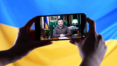 Nisan 2022 - Mariupol, Ukrayna. Başkan Volodymyr Zelensky 'nin Ukrayna bayrağı geçmişinde yaptığı akıllı telefon konuşmasını izliyorum. Haberler. Rus saldırganlığı. Savaş tehdidi..