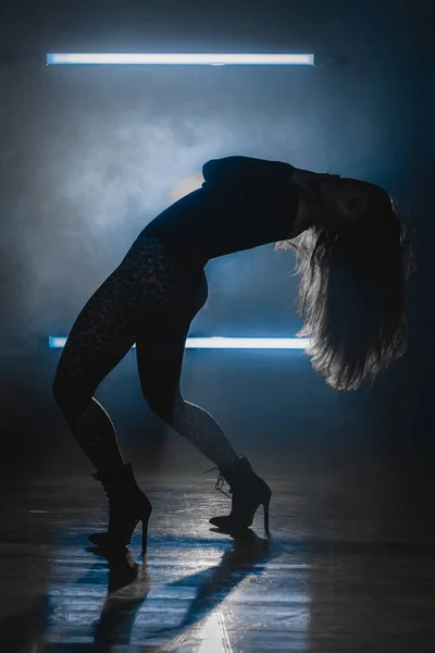 Сексуальная женщина танцует на фоне светящихся светильников. Она выглядит соблазнительно. Синяя дымная студия. — стоковое фото