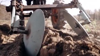 Çiftçi adam çalışıyor, bahçe çernozem tarlasında motorlu ünite motoblock ile çiftçilik yapıyor. Küçük ölçekli bir traktör, evde kullanılıyor. Arazi ekimi, patates ekme, toprak sürme. Tarım.