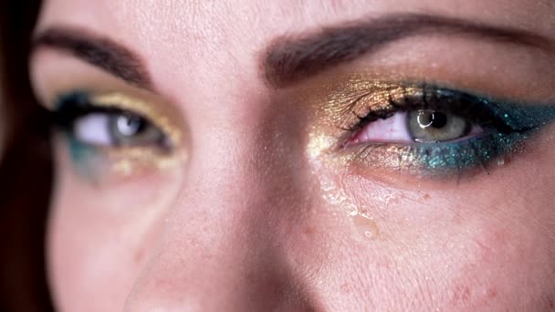 Ukrajinská žena zblízka, oči plačící, slzy stékající po tváři. Bolest, válka, zášť, frustrace. Žlutý a modrý make-up jako symbol Ukrajiny, vlajka. — Stock video