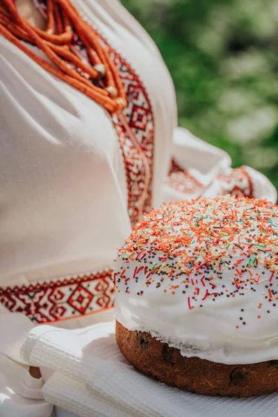 Mujer ucraniana sosteniendo en las manos pastel de Pascua. Señora en bordado vestido vyshivanka sobre fondo de la naturaleza. Símbolo de fiesta, religión y tradición. — Foto de Stock