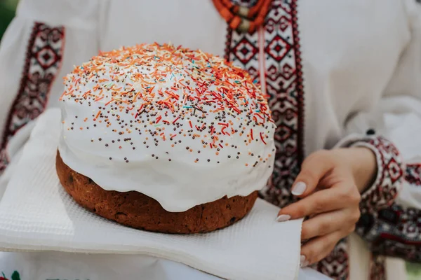 Ukrainka trzyma w rękach tort wielkanocny. Pani w hafcie vyshivanka sukienka na tle natury. Symbol wakacji, religii i tradycji. — Zdjęcie stockowe