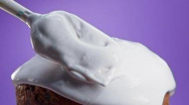 Döner Paskalya pastası, beyaz jöleli dekorasyon, geleneksel fırın. Bahar Hıristiyan dini bayramı. Lezzetli ev yapımı şenlikli tatlılar. Mor arkaplan.