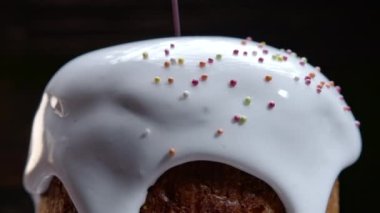 Dönüşümlü Paskalya pastası, beyaz jöleli dekorasyon ve renkli şeker serpiştirme, geleneksel fırın. Bahar Hıristiyan dini bayramı. Lezzetli ev yapımı şenlikli tatlılar. Siyah arkaplan.