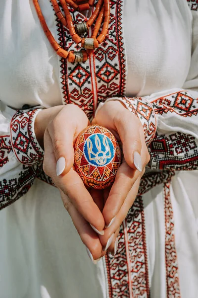 Mulher ucraniana que mantém em mãos ovos de Easter com o símbolo nacional da Ucrânia - decoração tridente. Senhora em bordado vestido vyshyvanka. — Fotografia de Stock