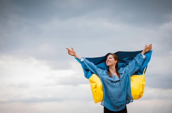 Mulher ucraniana sorridente com bandeira nacional no fundo do céu. Retrato de jovem senhora em azul bordado vyshyvanka. Espaço para cópia. Ucrânia, independência, liberdade, símbolo patriota, vitória na guerra. — Fotografia de Stock